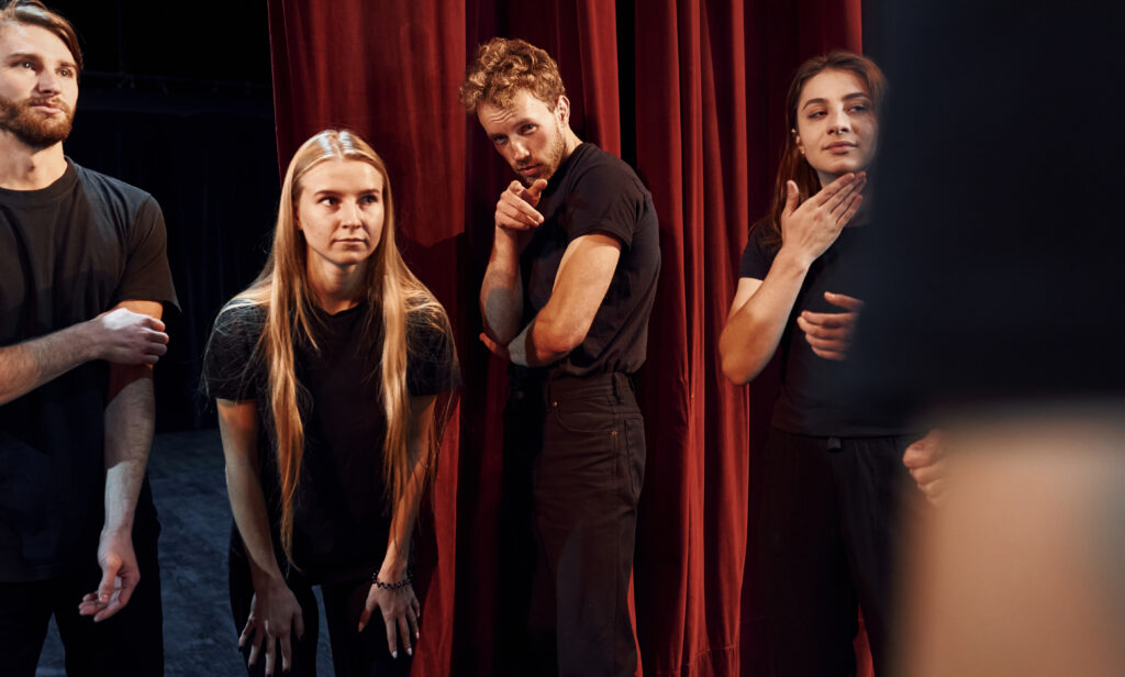 standing people against red curtains